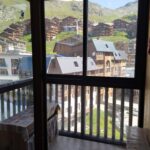 Se fra en træbalkon med udsigt over den maleriske landsby Saalbach. Scenen byder på en blanding af bygninger med træ- og metaltag mod grønne bakker og en klar blå himmel, der fanger essensen af skirejser i denne maleriske bjergrige region.