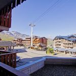 Fra balkonen udfolder den maleriske udsigt over Saalbach sig med sine charmerende bygninger i chalet-stil beliggende i en bjergby. Sneklædte tinder rejser sig majestætisk under en klar blå himmel, mens en skilift og snoede bjergstier antyder spændende skirejseeventyr.
