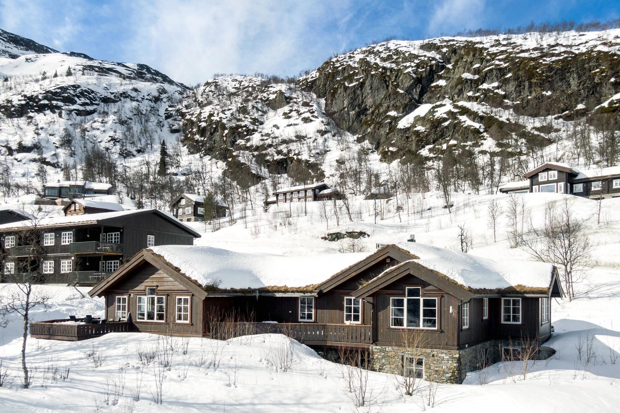 Et sneklædt bjerglandskab med flere træhytter spredt ud over bjergskråningen i Westendorf. Hytterne har snedækkede tage, og omgivelserne er dækket af hvid sne under en knaldblå himmel.