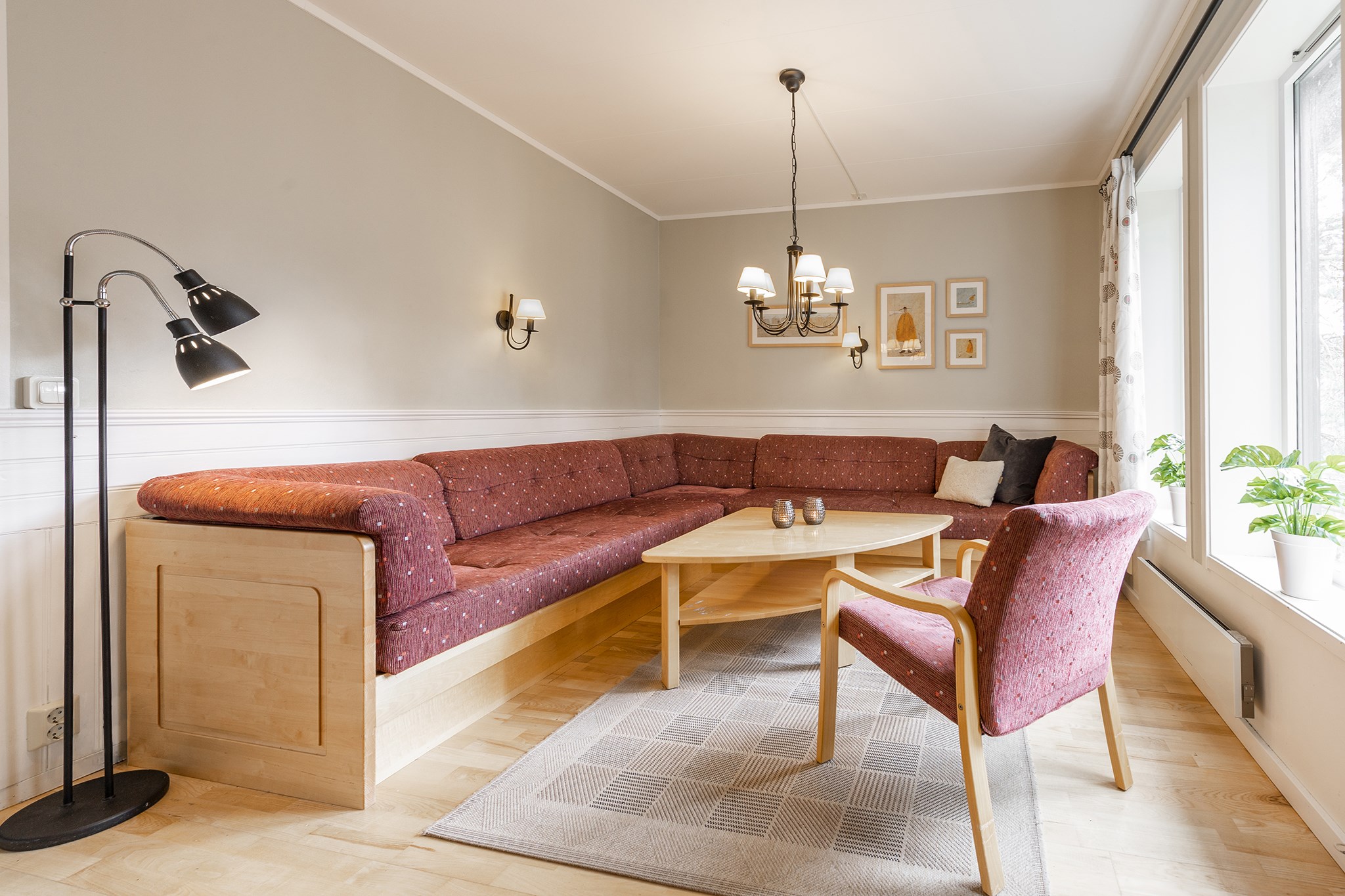 En hyggelig stue i Wagrain kan prale af en stor L-formet rødbrun sofa, et sofabord i træ og en matchende polstret stol. Med lyse vægge, loftslamper og vægkunst strømmer naturligt lys gennem vinduet. En nærliggende plante tilføjer stemningen – perfekt til afslapning efter skirejseeventyr.